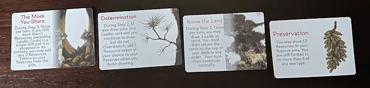 four Knowledge cards (black text on white background with a nature painting) on a dark wood table.