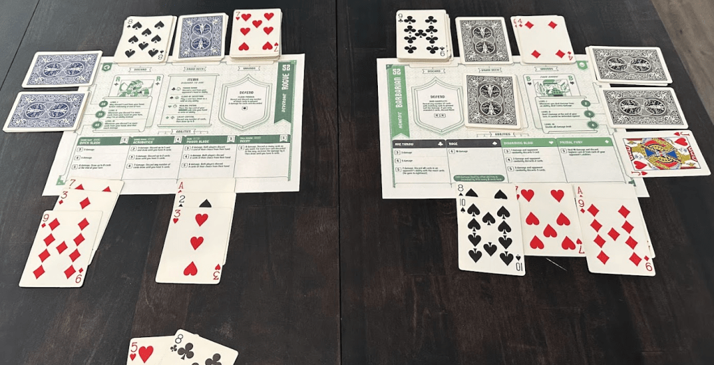 A tabletop view of a mid-game solo setup for '52 Duels', featuring cards and player sheets laid out. Each player area includes a mix of face-down and face-up playing cards along with character sheets showing abilities and actions.