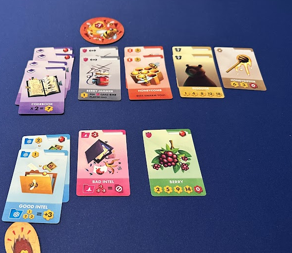 Several cards shown on a blue playmat, including Codebook, Berry Jammer, Honeycomb, Good Intel, Bad Intel, and Disguise.
